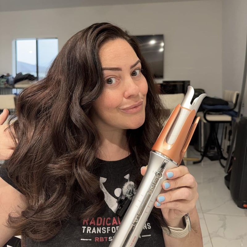 Woman holding a hair curler in a room with a TV and chairs.